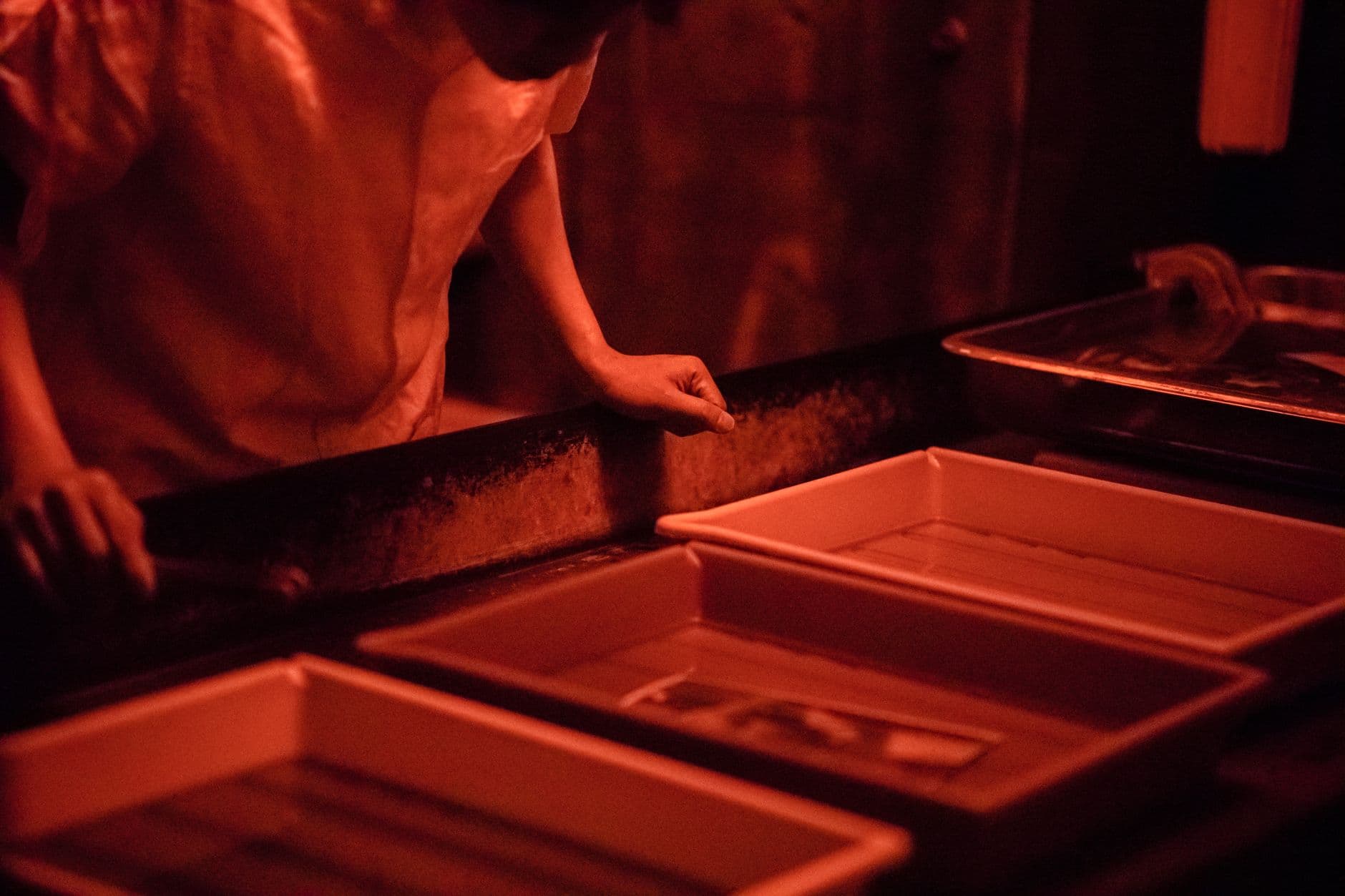Person developing photographs beside darkroom equipment.