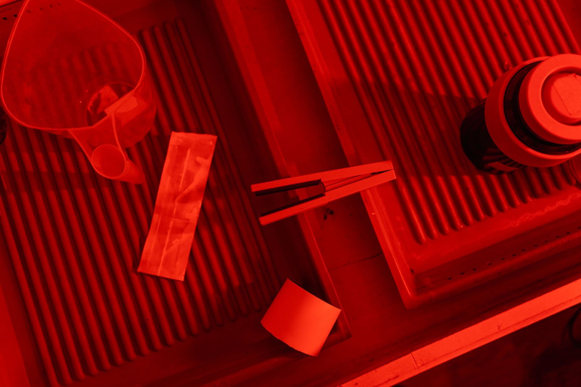Developing trays in a red-lit darkroom.