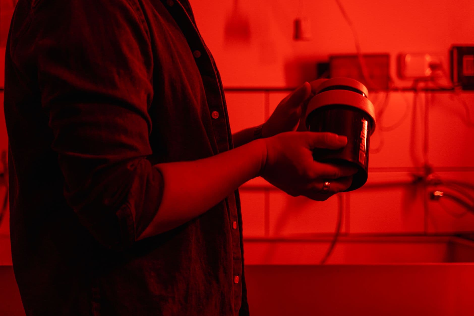Person working with a film development canister under red light.