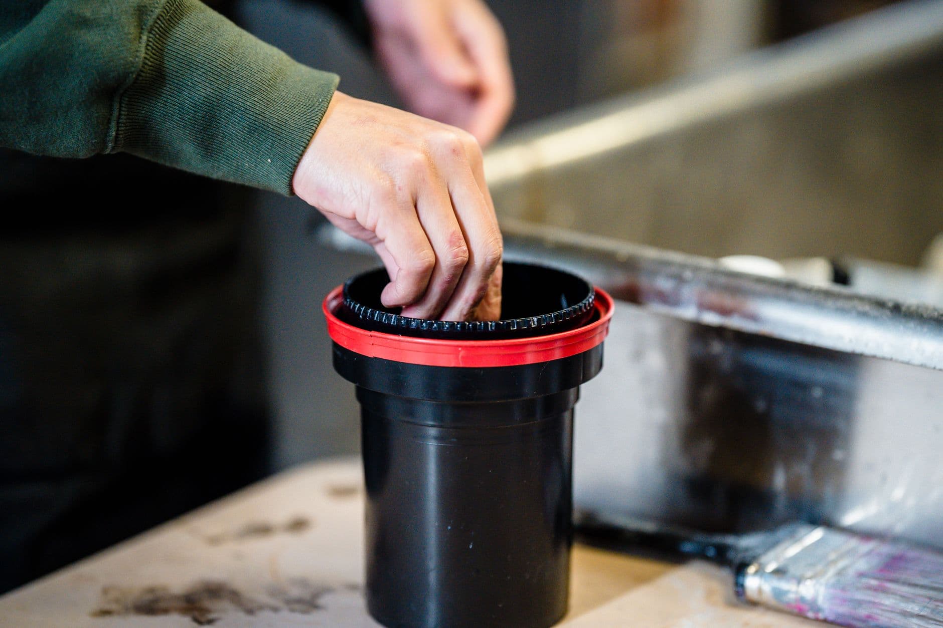 Hand placing film into a black developing tank.