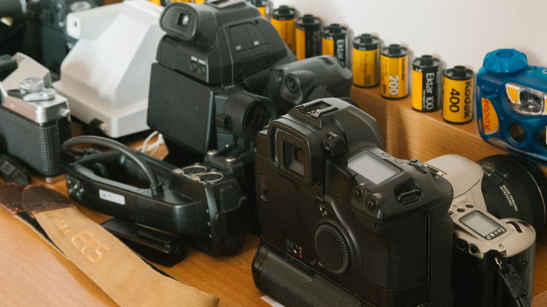 Vintage cameras and film rolls arranged on a wooden desk.
