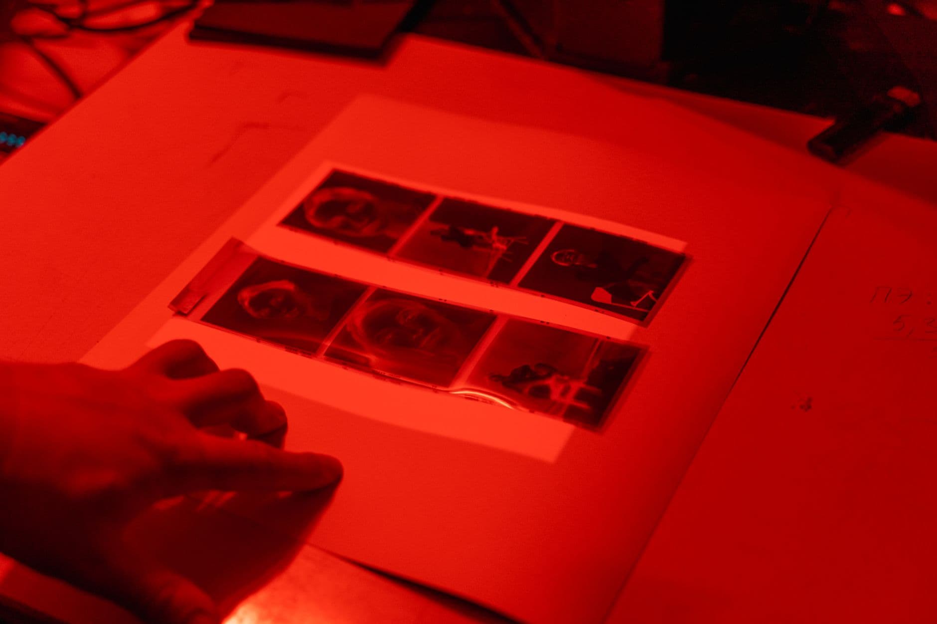 Hands holding photographic film strips over process notes.